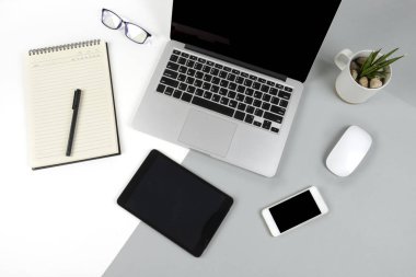 Dizüstü bilgisayar, dizüstü bilgisayar, dijital tablet ve modern iki ton (beyaz ve gri) arka plan üstünde hareket eden telefon ile ofis masaları.