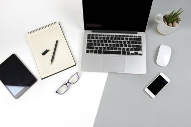 Dizüstü bilgisayar, dizüstü bilgisayar, dijital tablet ve modern iki ton (beyaz ve gri) arka plan üstünde hareket eden telefon ile ofis masaları.