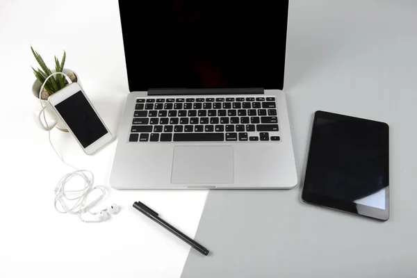 Mesa de oficina con ordenador portátil, tableta digital y teléfono móvil en un moderno fondo bicolor (blanco y gris) . —  Fotos de Stock