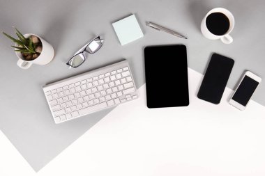 Ofis Masası klavye, cep telefonu, kalem, defter, dijital tablet ile düz yatıyordu fotoğrafı modern iki ton (beyaz ve gri) arka plan gözlük. Masaüstü ofis mockup kavramı.