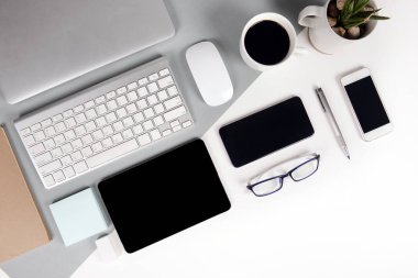 Ofis Masası klavye, cep telefonu, kalem, defter, dijital tablet ile düz yatıyordu fotoğrafı modern iki ton (beyaz ve gri) arka plan gözlük. Masaüstü ofis mockup kavramı.