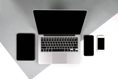 Ofis Masaları dizüstü bilgisayar, dizüstü bilgisayar, dijital tablet ve modern iki ton (beyaz ve gri) arka plan üstünde hareket eden telefon ile düz yatıyordu fotoğraf. Masaüstü ofis mockup kavramı.