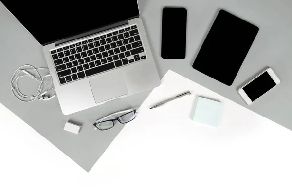 Flat lay foto de la mesa de Office con ordenador portátil, portátil, tableta digital, teléfono móvil, lápiz sobre fondo moderno de dos tonos (blanco y gris). Escritorio concepto de maqueta de oficina . — Foto de Stock
