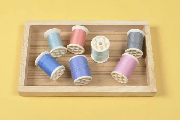 Flat lay of colored thread rolls for sewing on yellow background