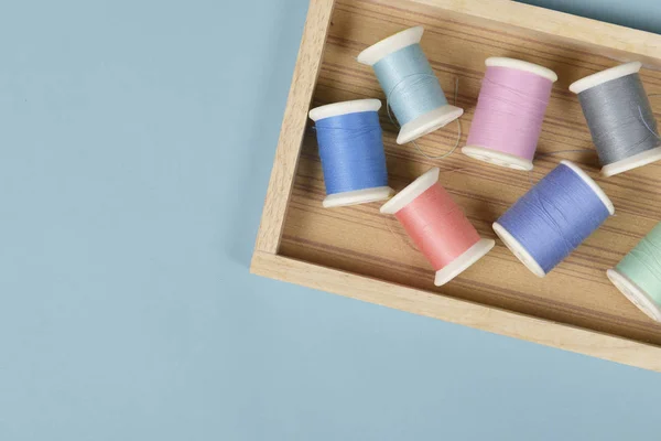 Flat lay of colored thread rolls for sewing on blue background,
