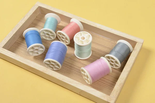 Colocación plana de rollos de hilo de colores para coser sobre fondo amarillo —  Fotos de Stock