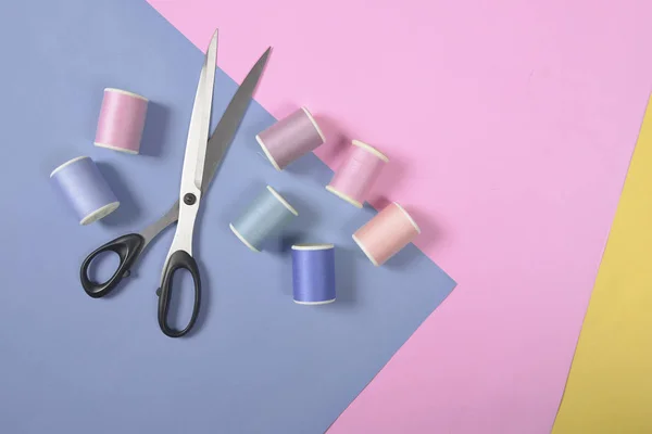 Flat lay of colored thread rolls and Scissors for sewing on two