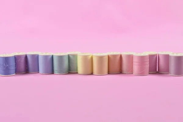 Pose plate de rouleaux de fil colorés pour la couture sur fond rose , — Photo