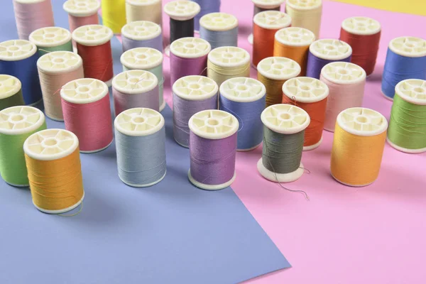 Flat lay of colored thread rolls for sewing on two tone backgrou