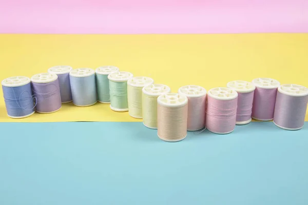 Flache Lage farbiger Fadenrollen zum Nähen auf zweifarbigem Hintergrund — Stockfoto