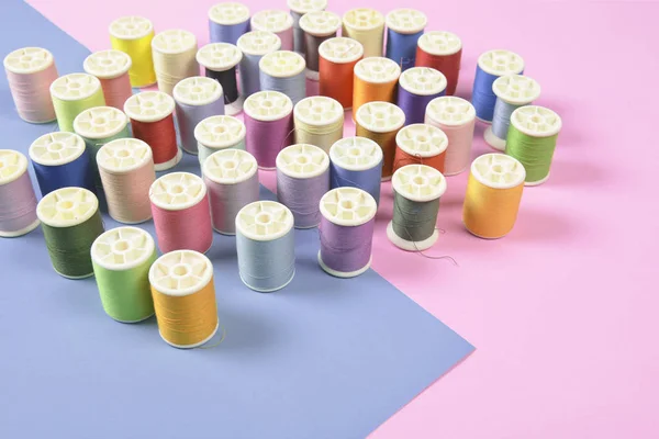 Flat lay of colored thread rolls for sewing on two tone backgrou