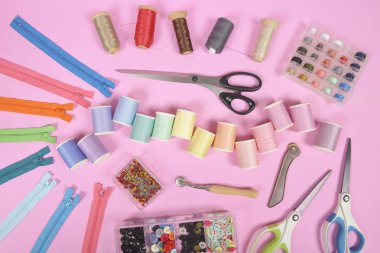 Dikiş malzemesi düz lay ölçme bant, fermuar, PIN makas içerir ve renkli iplik dikiş için pembe arka plan, dikiş ve iğne işi konsepti üzerine alır..