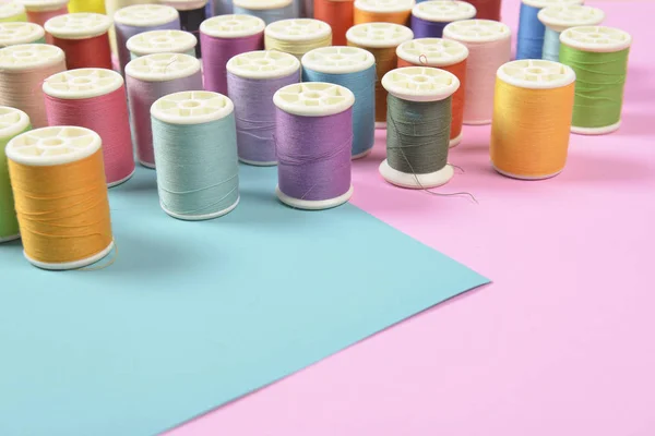 Flat lay of colored thread rolls for sewing on two tone background, Sewing and needlework concept.