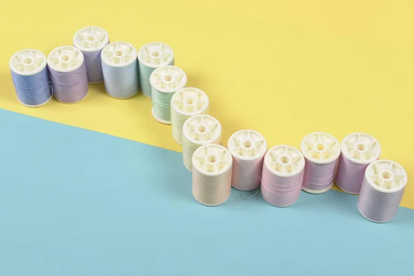 Flat lay of colored thread rolls for sewing on two tone background, Sewing and needlework concept.