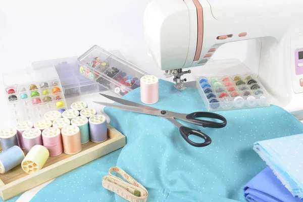 Sewing machine and colorful thread rolls, scissors, fabric and a — Stock Photo, Image