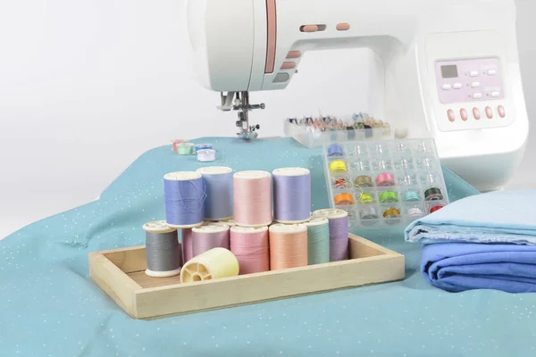 Sewing machine and colorful thread rolls, scissors, fabric and a — Stock Photo, Image