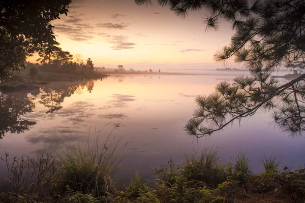 Raios de nascer do sol sobre o lago com névoa de reflexão sobre a água , — Fotografia de Stock
