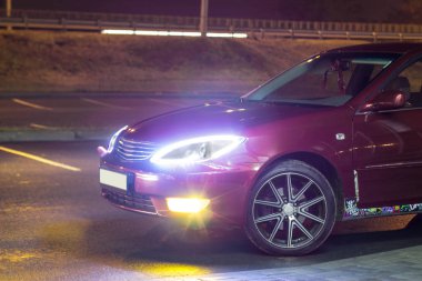 Kiraz kırmızı 4 kapılı aile d-sınıfı sedan Toyota Camry beşinci nesil xv30 2001-2006 led farlar ve 18 inç jantlar büyük jantlar ile yaz bir arka plan üzerinde yeşil bir alan ve orman üzerinde ayakta