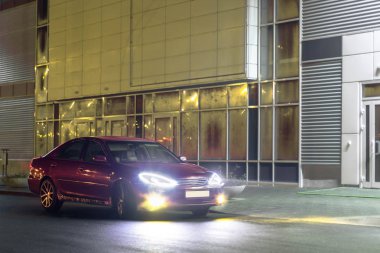 Kiraz kırmızı 4 kapılı aile d-sınıfı sedan Toyota Camry beşinci nesil xv30 2001-2006 led farlar ve 18 inç jantlar büyük jantlar ile yaz bir arka plan üzerinde yeşil bir alan ve orman üzerinde ayakta