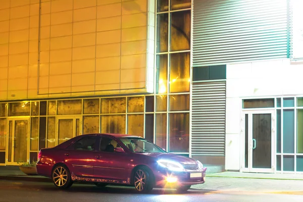 Kiraz kırmızı 4 kapılı aile d-sınıfı sedan Toyota Camry beşinci nesil xv30 2001-2006 led farlar ve 18 inç jantlar büyük jantlar ile yaz bir arka plan üzerinde yeşil bir alan ve orman üzerinde ayakta