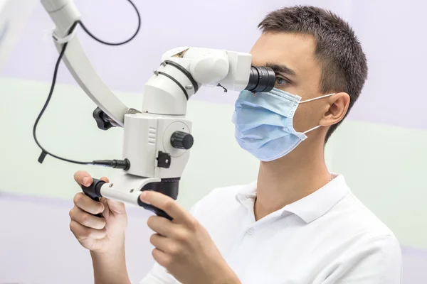 Doktor diş bir mikroskop kullanarak — Stok fotoğraf