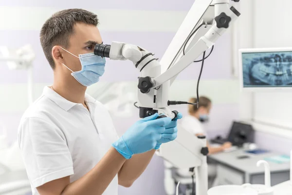 Dentista usando microscópio dentário — Fotografia de Stock