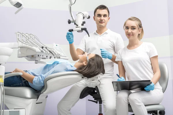 Dentist, assistant and patient in clinic — Stock Photo, Image