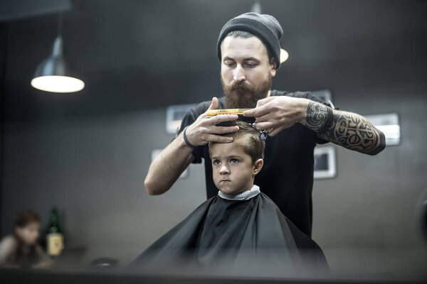 Haircut of small boy in barbershop
