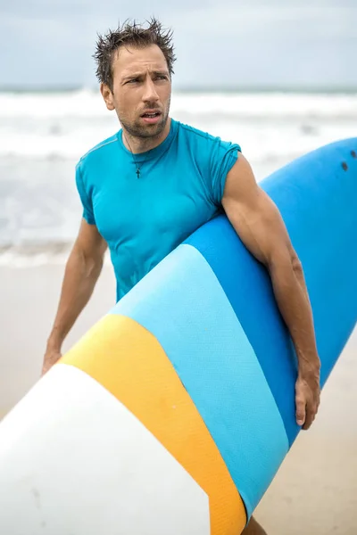 Uomo con tavola da surf sulla spiaggia — Foto Stock