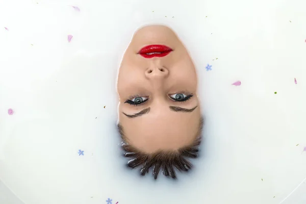 Schitterend meisje in het bad vol met water met melk en enkele colorf — Stockfoto