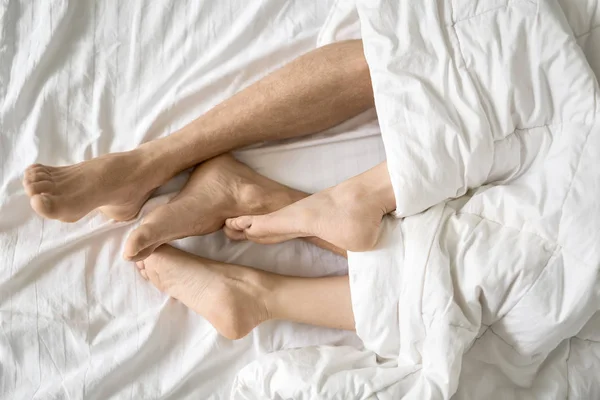 Nohy milenců pod dekou — Stock fotografie