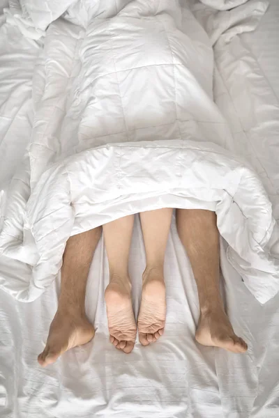 Jambes d'amoureux sous couverture — Photo