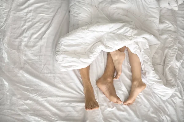 Pernas de amantes sob cobertor — Fotografia de Stock