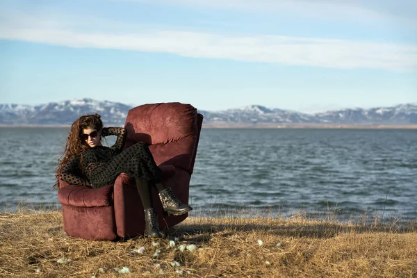 Girl sits on armchair outdoors — Stock Photo, Image