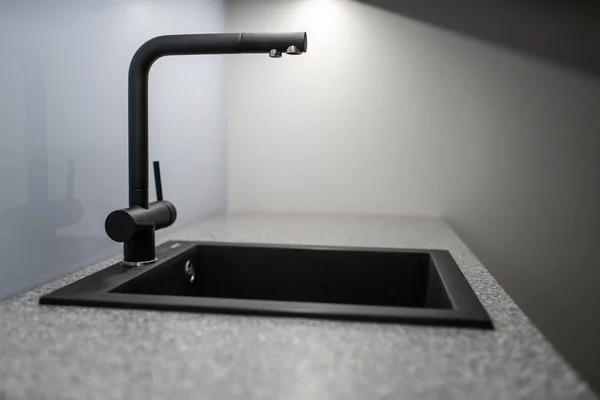 Luminous gray kitchen with black sink and faucet — Stock Photo, Image