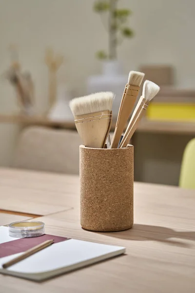 Closeup view at paint brushes and stationery on table — Stock Photo, Image