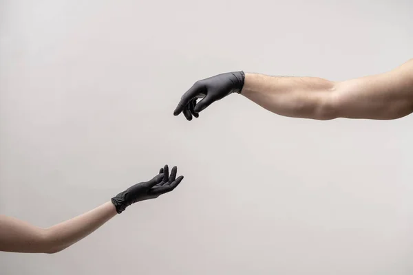 Hands in black silicone gloves stretches to each other to touch — Stock Photo, Image