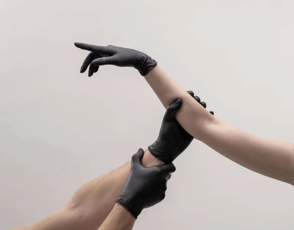 Чоловіча і жіноча рука в чорних рукавицях. Тримайтеся один одного . — стокове фото