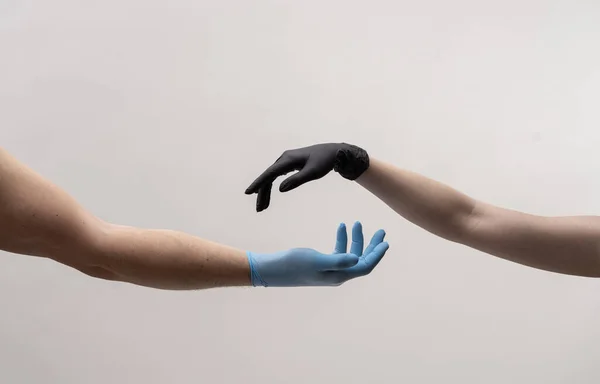 Mužská a ženská ruka v černých rukavicích se natahují, aby se navzájem dotýkaly. — Stock fotografie