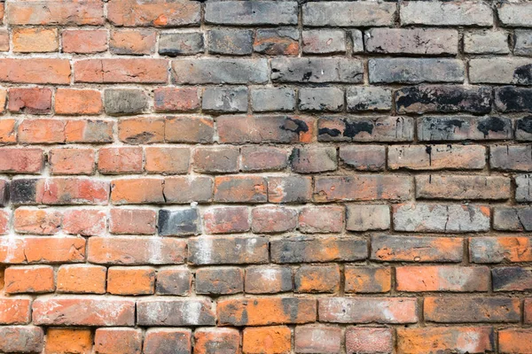 Rojo viejo pared de ladrillo desgastado con manchas negras textura fondo . — Foto de Stock