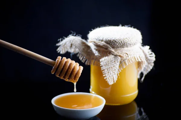 Een pot geurende honing op een zwarte lijst — Stockfoto