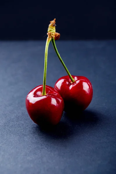 Zwei reife und schmackhafte rote Kirschen auf blauem Hintergrund — Stockfoto