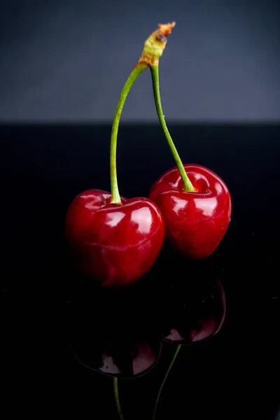 Zwei reife und schmackhafte rote Kirschen auf schwarzem Hintergrund — Stockfoto