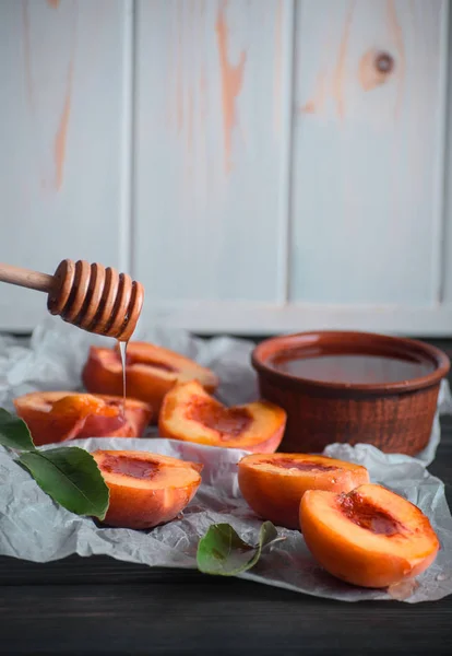 Rijpe perziken op een tafel met lekkere honing — Stockfoto