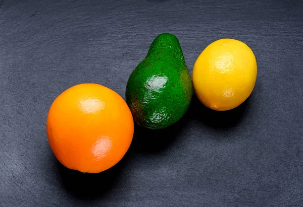 Спелые апельсин, лимон и авакадо на доске — стоковое фото