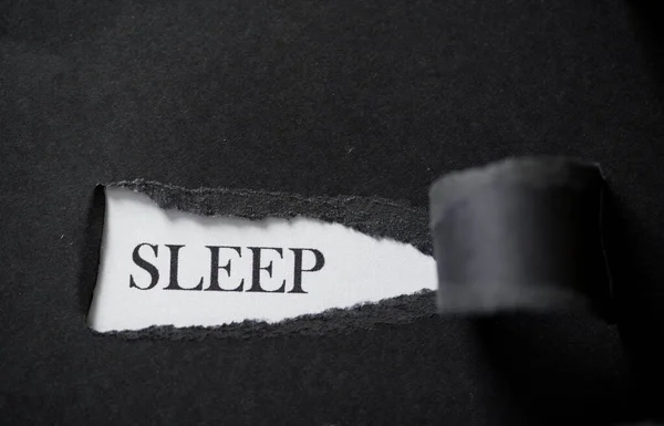 Слово SLEEP напечатано на белом фоне с черной порванной бумагой . — стоковое фото