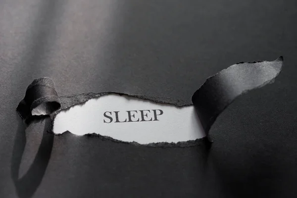 Word SLEEP impreso sobre un fondo blanco con papel negro desgarrado . —  Fotos de Stock