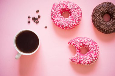 Pembe kremalı lezzetli çörekler ve beyaz ahşap arka planda bir fincan aromalı kahve..