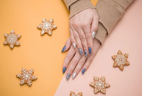 Stijlvolle trendy vrouwelijke manicure op roze achtergrond. Meisje houdt hand in hand macaron koekjes. Bovenaanzicht, vlak lay. — Stockfoto