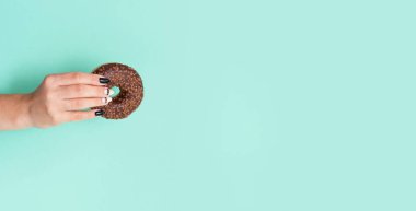 Renkli arka planda kremalı iştah açıcı çörekler ve güzel manikürlü kadın elleri..